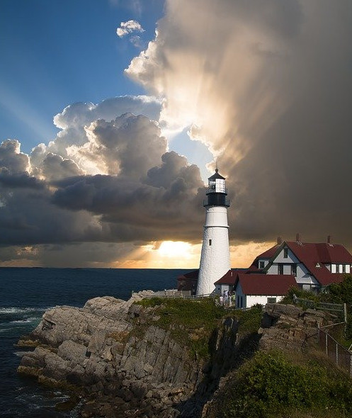 Clouds parting on a lighthouse near the ocean